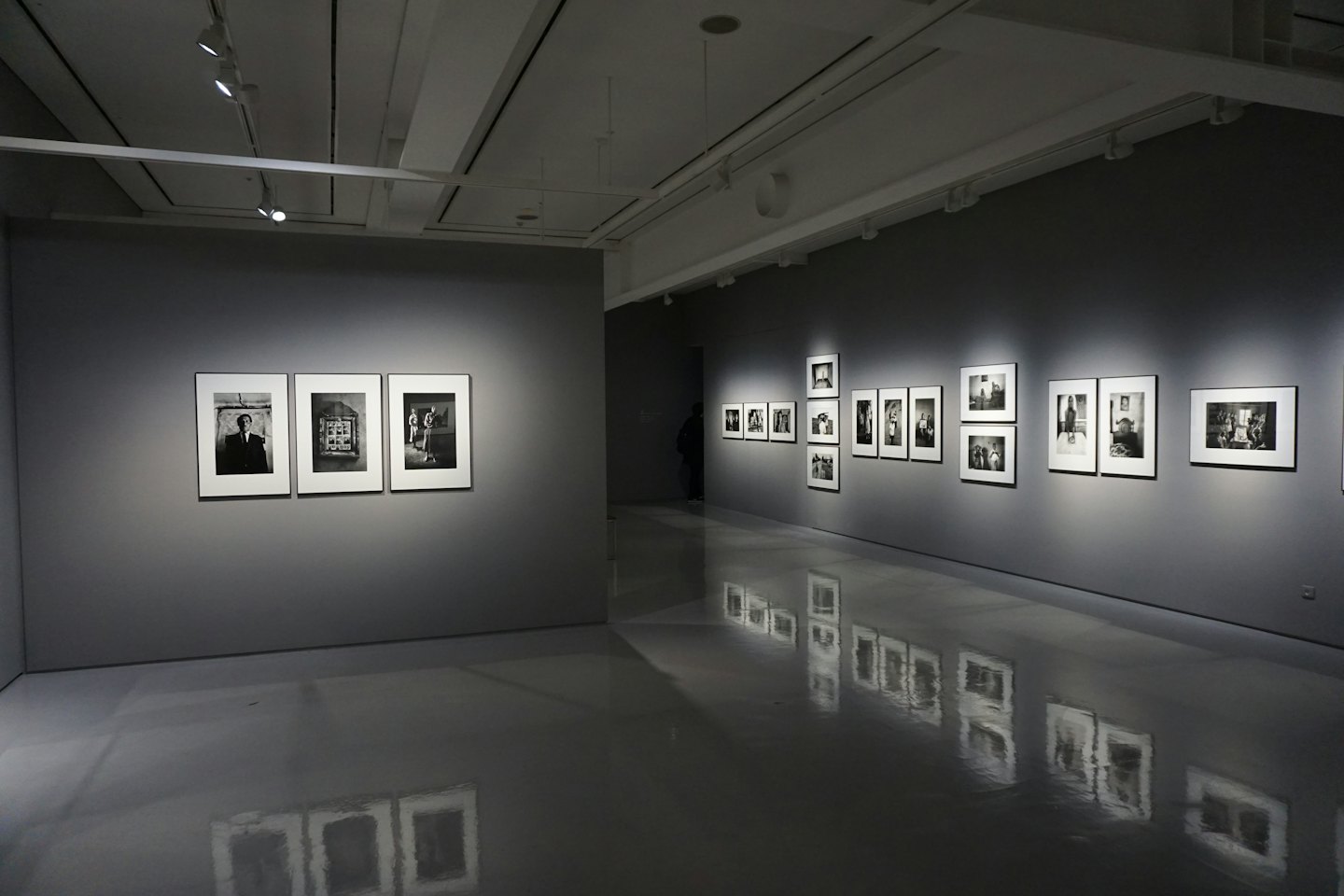 Moderne Kunstgalerie mit Schwarz-Weiß-Fotografien an grauen Wänden.